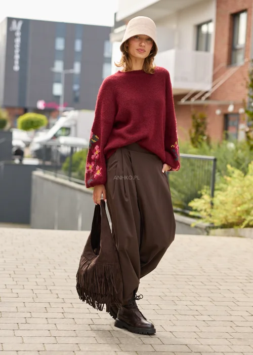 Sweter damski oversize w bordowym kolorze, z szerokimi rękawami ozdobionymi kolorowym haftem w kwiatowe motywy.