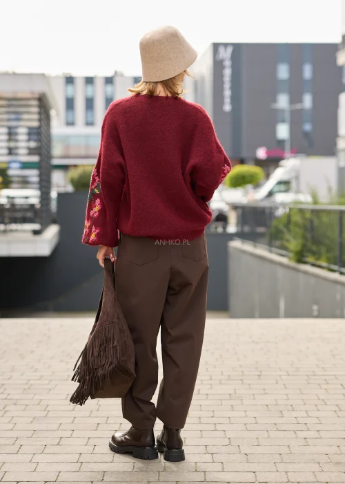 Sweter damski oversize w bordowym kolorze, z szerokimi rękawami ozdobionymi kolorowym haftem w kwiatowe motywy.