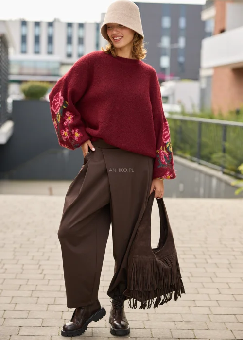 Sweter damski oversize w bordowym kolorze, z szerokimi rękawami ozdobionymi kolorowym haftem w kwiatowe motywy.