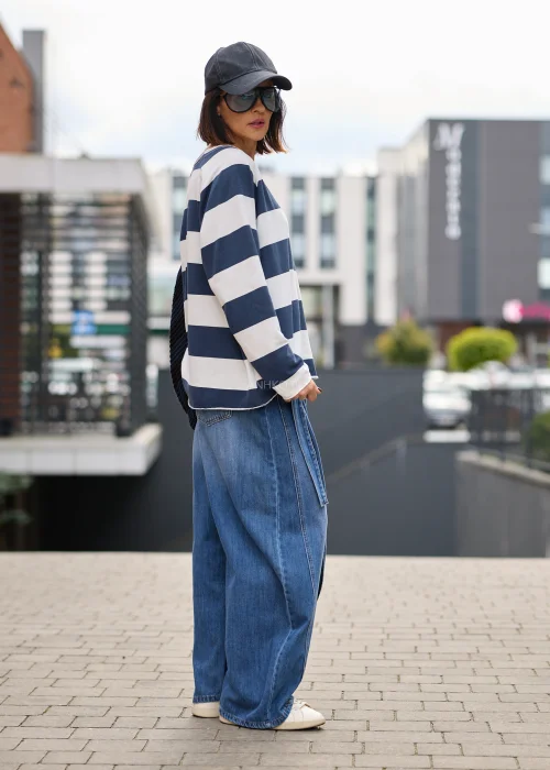 Jeansy damskie wide leg w niebieskim denimie, z asymetrycznym kopertowym przodem, wysokim stanem i szerokimi nogawkami.