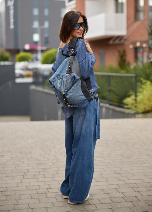 Jeansy damskie wide leg w niebieskim denimie, z asymetrycznym kopertowym przodem, wysokim stanem i szerokimi nogawkami.