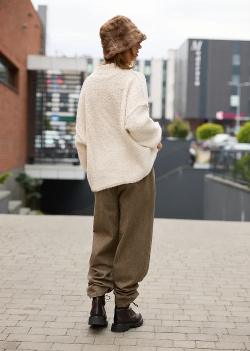 Dzianinowy sweter damski oversize w kremowym kolorze, o miękkiej, wyraźnie teksturowanej strukturze, z obniżoną linią ramion, długimi rękawami i prostym dekoltem pod szyję.
