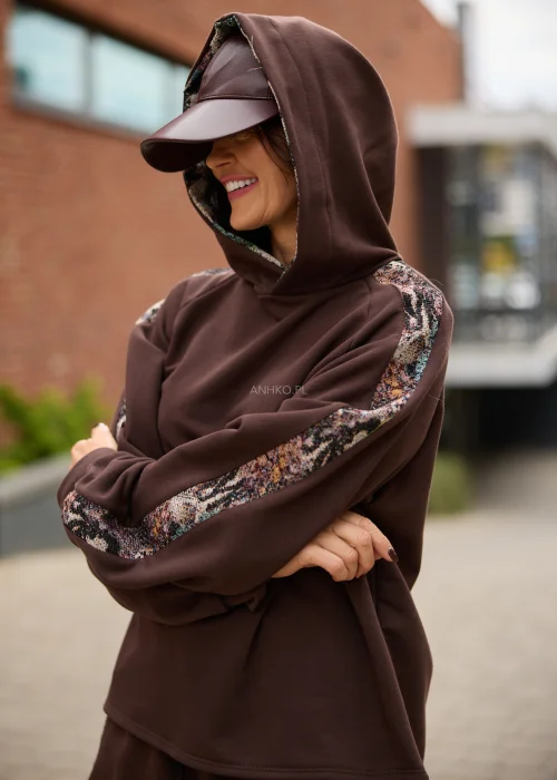Bluza damska oversize w czekoladowym brązie z kapturem i kontrastowymi, wielokolorowymi wstawkami o gobelinowej strukturze na rękawach.