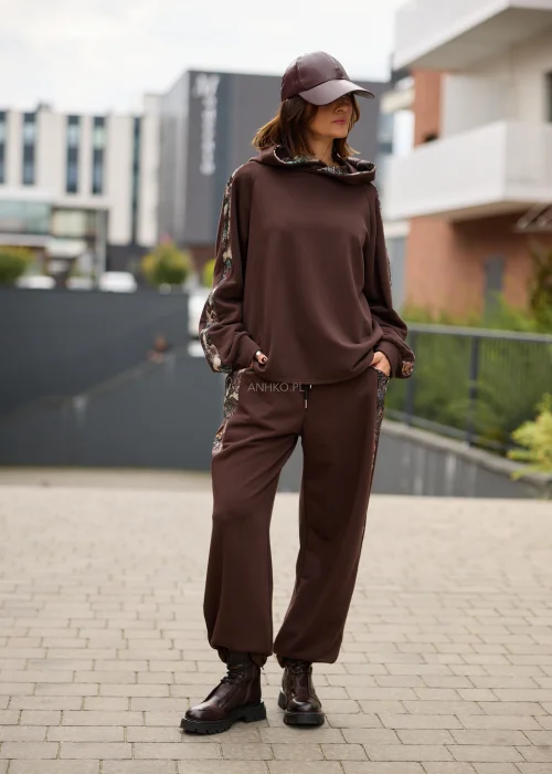 Bluza damska oversize w czekoladowym brązie z kapturem i kontrastowymi, wielokolorowymi wstawkami o gobelinowej strukturze na rękawach.