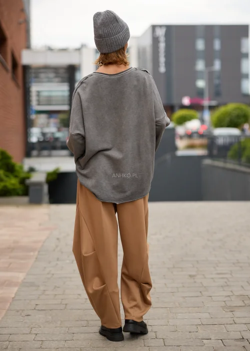 Bluzka damska oversize w kolorze spranej grafitowej szarości, z dekoltem w serek, obniżoną linią ramion, długimi luźnymi rękawami, ozdobnymi przeszyciami oraz asymetrycznym, lekko wydłużonym tyłem.