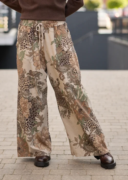 Spodnie damskie z szerokimi nogawkami w beżowej kolorystyce, z patchworkowym wzorem łączącym motywy kwiatowe, paisley i animal print oraz regulacją w pasie.