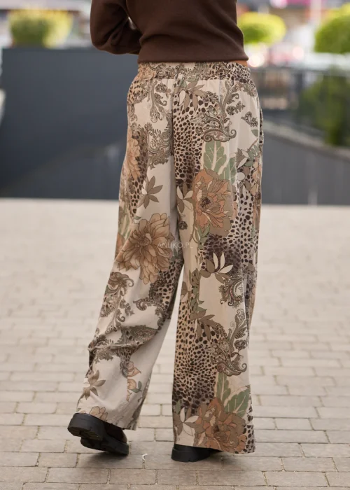 Spodnie damskie z szerokimi nogawkami w beżowej kolorystyce, z patchworkowym wzorem łączącym motywy kwiatowe, paisley i animal print oraz regulacją w pasie.