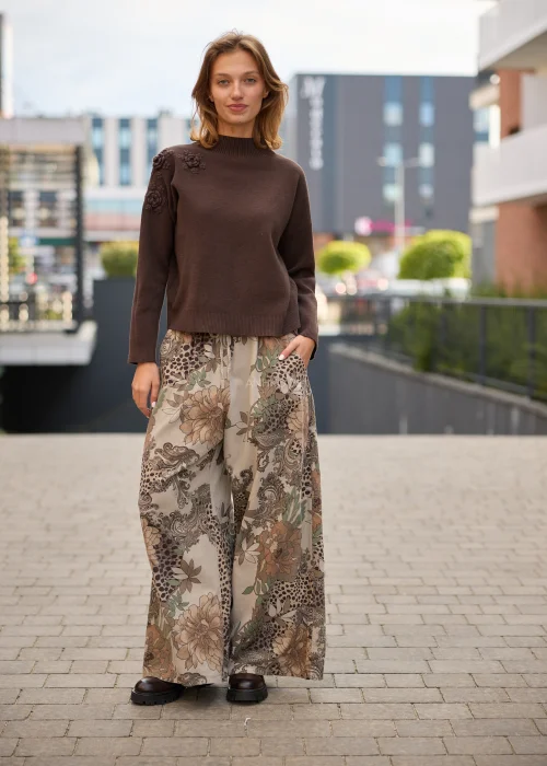Sweter damski w kolorze czekoladowego brązu, o luźnym fasonie z półgolfem i długimi rękawami, ozdobiony przestrzennymi kwiatowymi aplikacjami na ramieniu.