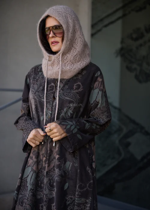 Dzianinowy kaptur damski typu balaclava w kolorze beżowo-taupe, o puszystej fakturze i ażurowym splocie, z szerokim prążkowanym wykończeniem przy szyi oraz długimi troczkami do wiązania.