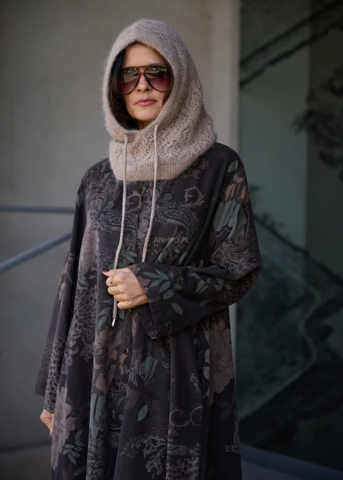 Dzianinowy kaptur damski typu balaclava w kolorze beżowo-taupe, o puszystej fakturze i ażurowym splocie, z szerokim prążkowanym wykończeniem przy szyi oraz długimi troczkami do wiązania.