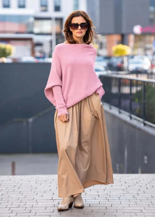Pudroworóżowy sweter damski oversize o kroju nietoperzowym z asymetrycznym dołem, stylizacja z jeansami.