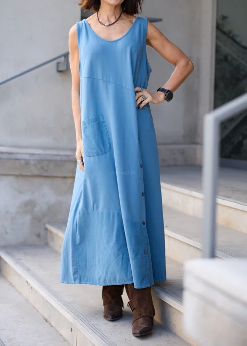 Sukienka damska maxi w kolorze przygaszonego błękitu, o mocno oversize’owym fasonie, z długimi rękawami, okrągłym dekoltem, asymetryczną warstwą materiału, pionowym rzędem guzików i dużą naszywaną kieszenią.