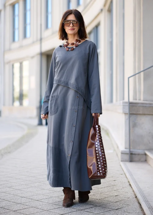 Sukienka damska maxi w kolorze grafitowoszarym, o mocno oversize’owym fasonie, z długimi rękawami, okrągłym dekoltem, asymetryczną warstwą materiału, pionowym rzędem guzików i dużą naszywaną kieszenią.