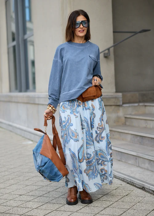 Bawełniana bluza damska oversize w spranym odcieniu niebieskiego, z okrągłym dekoltem, obniżoną linią ramion, długimi rękawami oraz dużą naszywaną kieszenią na piersi z klapką i asymetrycznym dołem.