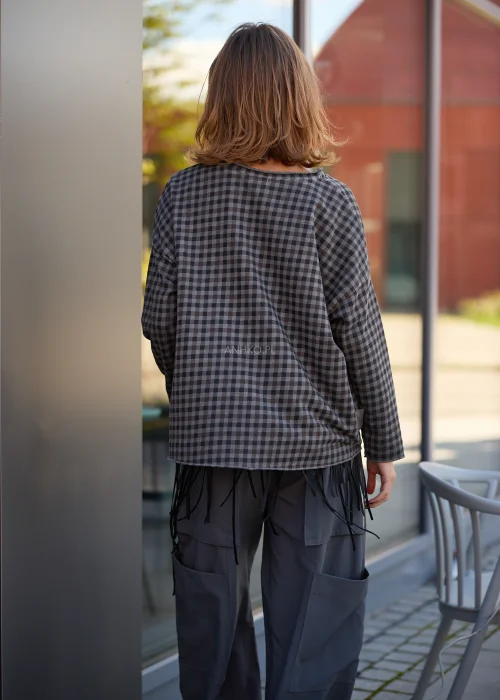 Bluzka damska oversize w drobną kratkę w odcieniach grafitu i szarości, z okrągłym dekoltem, obniżoną linią ramion, długimi szerokimi rękawami oraz luźnym, swobodnie opadającym fasonem.