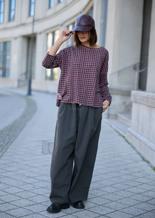 Bluzka damska oversize w drobną kratkę w odcieniach przygaszonego różu, fioletu i grafitu, z okrągłym dekoltem, obniżoną linią ramion, długimi rękawami, surowym wykończeniem brzegów oraz luźnym fasonem.