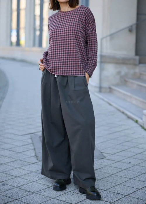 Bluzka damska oversize w drobną kratkę w odcieniach przygaszonego różu, fioletu i grafitu, z okrągłym dekoltem, obniżoną linią ramion, długimi rękawami, surowym wykończeniem brzegów oraz luźnym fasonem.
