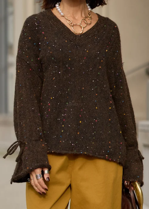 Sweter damski oversize z miękkiej, lekko puszystej dzianiny w kolorze ciemnego czekoladowego brązu, ozdobiony drobnymi, wielokolorowymi akcentami przypominającymi konfetti, z dekoltem w serek, obniżoną linią ramion