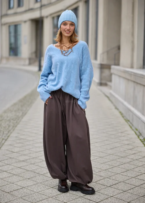 Sweter damski oversize z miękkiej, puszystej dzianiny w kolorze jasnego błękitu, z szerokim dekoltem w serek, obniżoną linią ramion, długimi rękawami zakończonymi szerokimi prążkowanymi mankietami