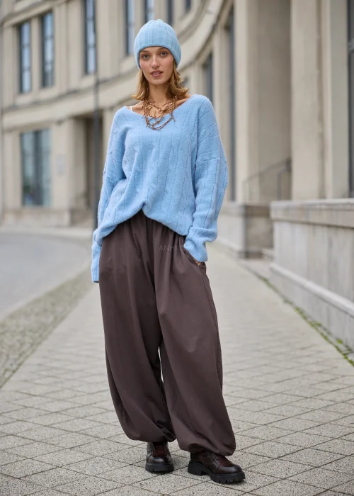 Sweter damski oversize z miękkiej, puszystej dzianiny w kolorze jasnego błękitu, z szerokim dekoltem w serek, obniżoną linią ramion, długimi rękawami zakończonymi szerokimi prążkowanymi mankietami