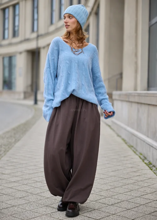 Sweter damski oversize z miękkiej, puszystej dzianiny w kolorze jasnego błękitu, z szerokim dekoltem w serek, obniżoną linią ramion, długimi rękawami zakończonymi szerokimi prążkowanymi mankietami