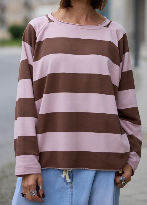 Bluza damska oversize w szerokie poziome pasy w kolorze pudrowego różu i czekoladowego brązu, z okrągłym dekoltem, długimi rękawami oraz surowo wykończonym dołem i mankietami.