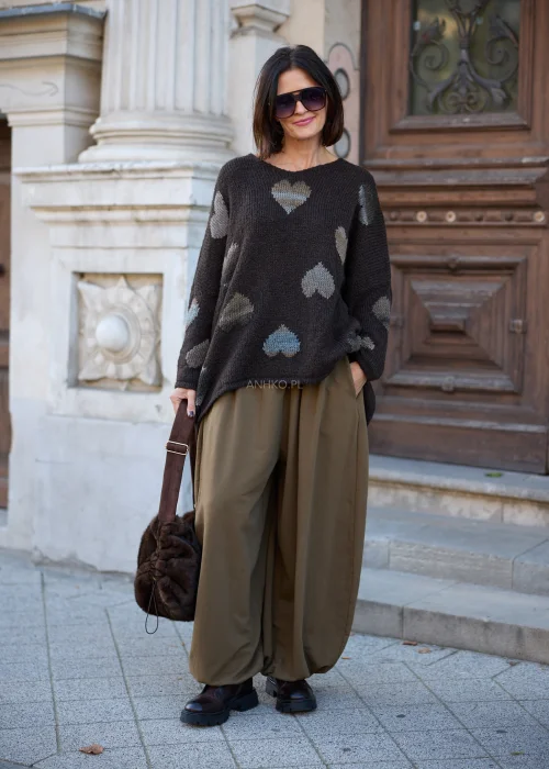 Sweter damski oversize z miękkiej dzianiny o wyrazistym splocie w kolorze ciemnobrązowym, ozdobiony nieregularnie rozmieszczonymi, dzianinowymi sercami w odcieniach beżu, szarości i błękitu, z szerokim okrągłym dekoltem, mocno obniżoną linią ramion
