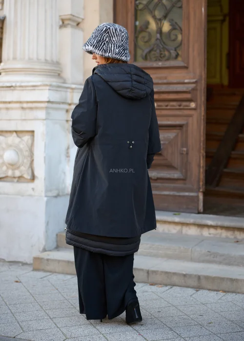 Płaszcz damski oversize w kolorze czarnym, o długim, prostym fasonie, z obszernym kapturem ze sznurkami, zapięciem na zamek błyskawiczny oraz warstwową konstrukcją łączącą gładki materiał z pikowanymi elementami.