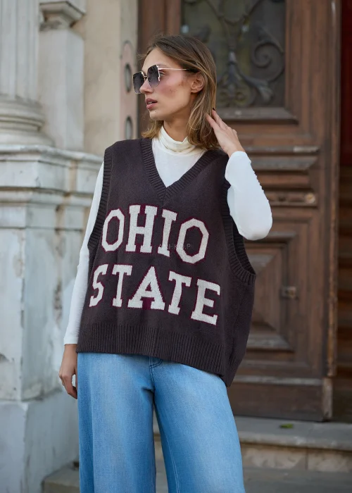 Dzianinowa kamizelka damska oversize w kolorze ciemnobrązowym, z dekoltem w serek, szerokimi otworami na ramiona i dużym napisem OHIO STATE w odcieniach kremu i bordo.