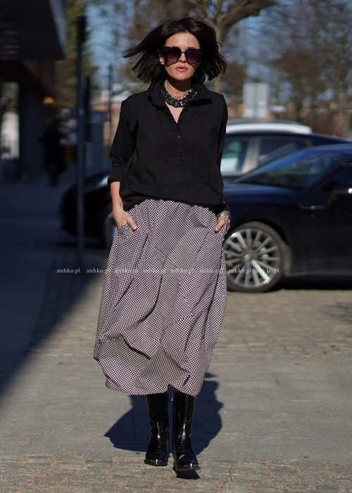 Czarna koszula damska oversize z kołnierzykiem i przeszyciem poniżej biustu, zestawiona z czarno-białą spódnicą w geometryczny wzór w miejskiej stylizacji.