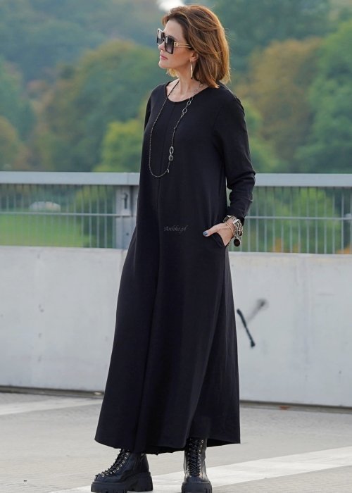 Czarny kombinezon damski z długim rękawem i bardzo szeroką nogawką, luźny fason w stylizacji z ciężkimi botkami na platformie.