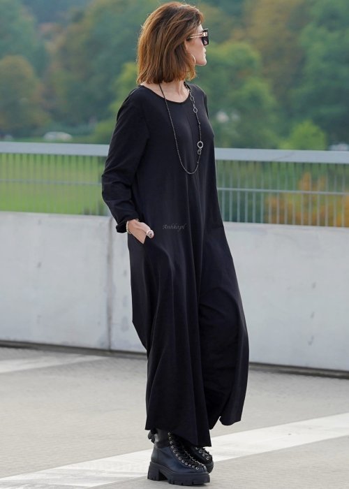 Czarny kombinezon damski z długim rękawem i bardzo szeroką nogawką, luźny fason w stylizacji z ciężkimi botkami na platformie.