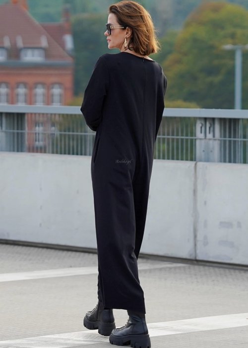 Czarny kombinezon damski z długim rękawem i bardzo szeroką nogawką, luźny fason w stylizacji z ciężkimi botkami na platformie.