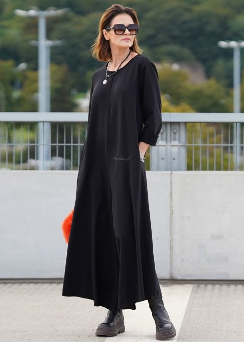 Czarny kombinezon damski z długim rękawem i bardzo szeroką nogawką, luźny fason w stylizacji z ciężkimi botkami na platformie.