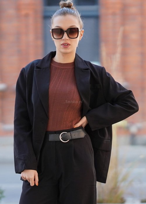 Czarna marynarka damska oversize o klasycznym kroju, stylizowana z eleganckimi spodniami i okularami przeciwsłonecznymi w miejskim looku.