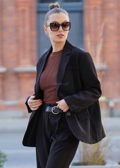 Czarna marynarka damska oversize o klasycznym kroju, stylizowana z eleganckimi spodniami i okularami przeciwsłonecznymi w miejskim looku.