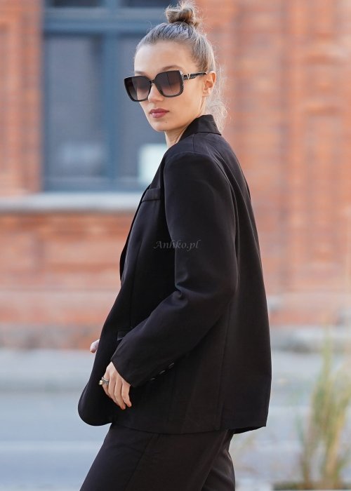 Czarna marynarka damska oversize o klasycznym kroju, stylizowana z eleganckimi spodniami i okularami przeciwsłonecznymi w miejskim looku.
