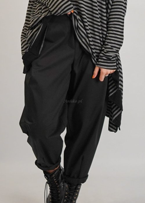 Czarne spodnie damskie z elastycznym pasem i zwężaną nogawką, zestawione z oversize bluzką i botkami w nowoczesnej stylizacji miejskiej.