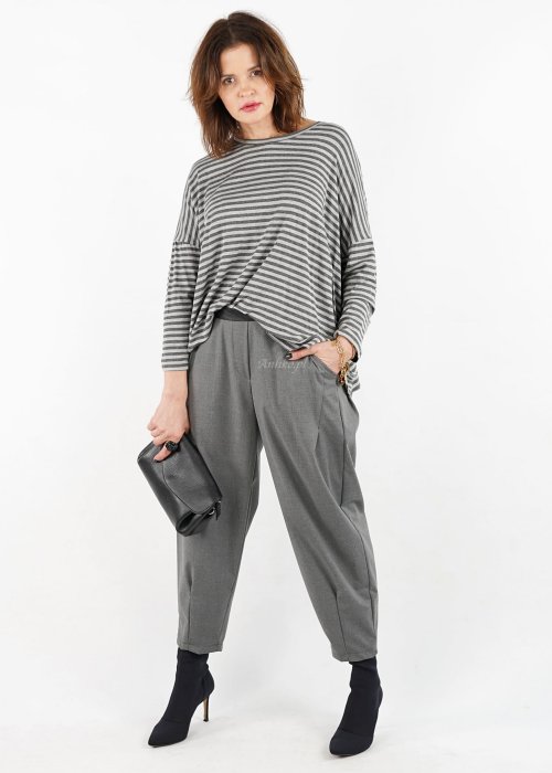 Szare spodnie damskie z elastycznym pasem i zwężaną nogawką, zestawione z oversize bluzką i botkami w nowoczesnej stylizacji miejskiej.