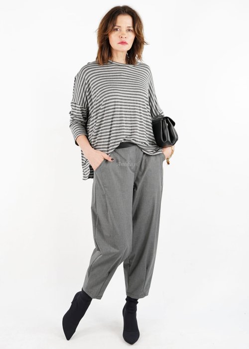 Szare spodnie damskie z elastycznym pasem i zwężaną nogawką, zestawione z oversize bluzką i botkami w nowoczesnej stylizacji miejskiej.