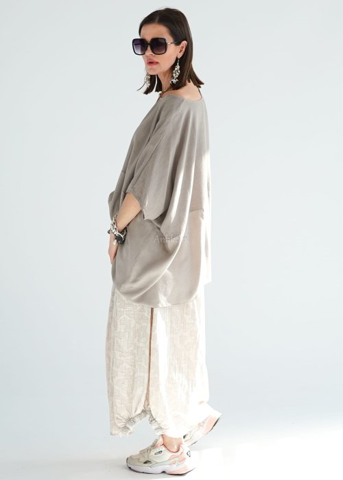 Bluzka oversize w kolorze taupe z szerokim rękawem i luźnym krojem. Stylizacja z jasną spódnicą i biżuterią w stylu boho.