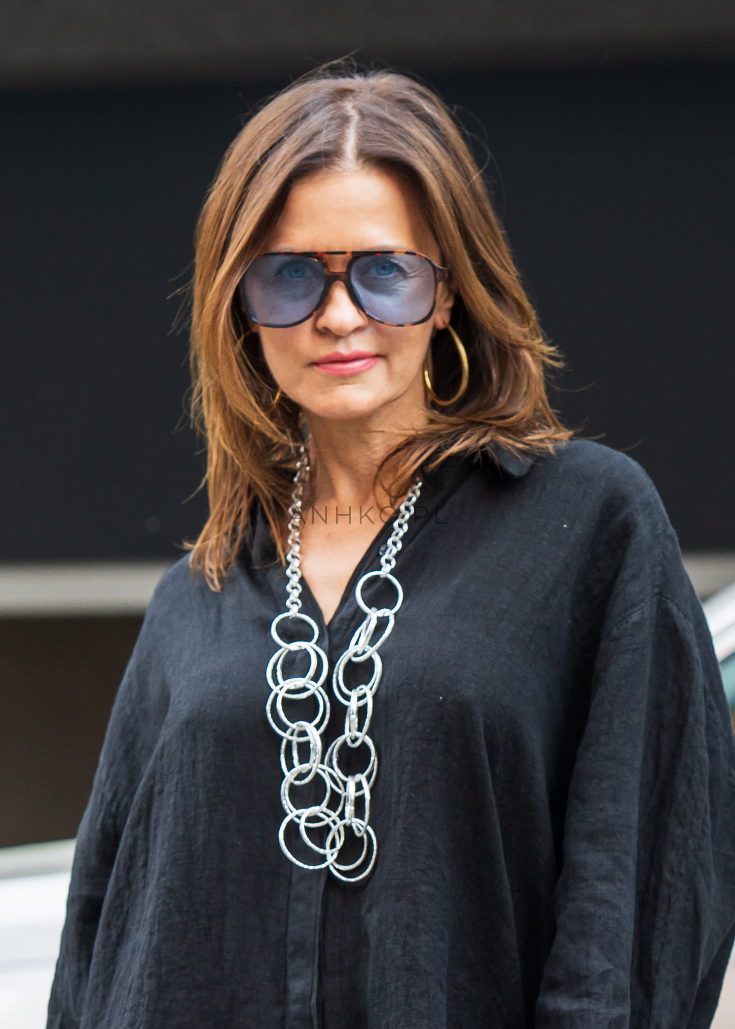 Kobieta w czarnej tunice i srebrnym naszyjniku z dużych ogniw