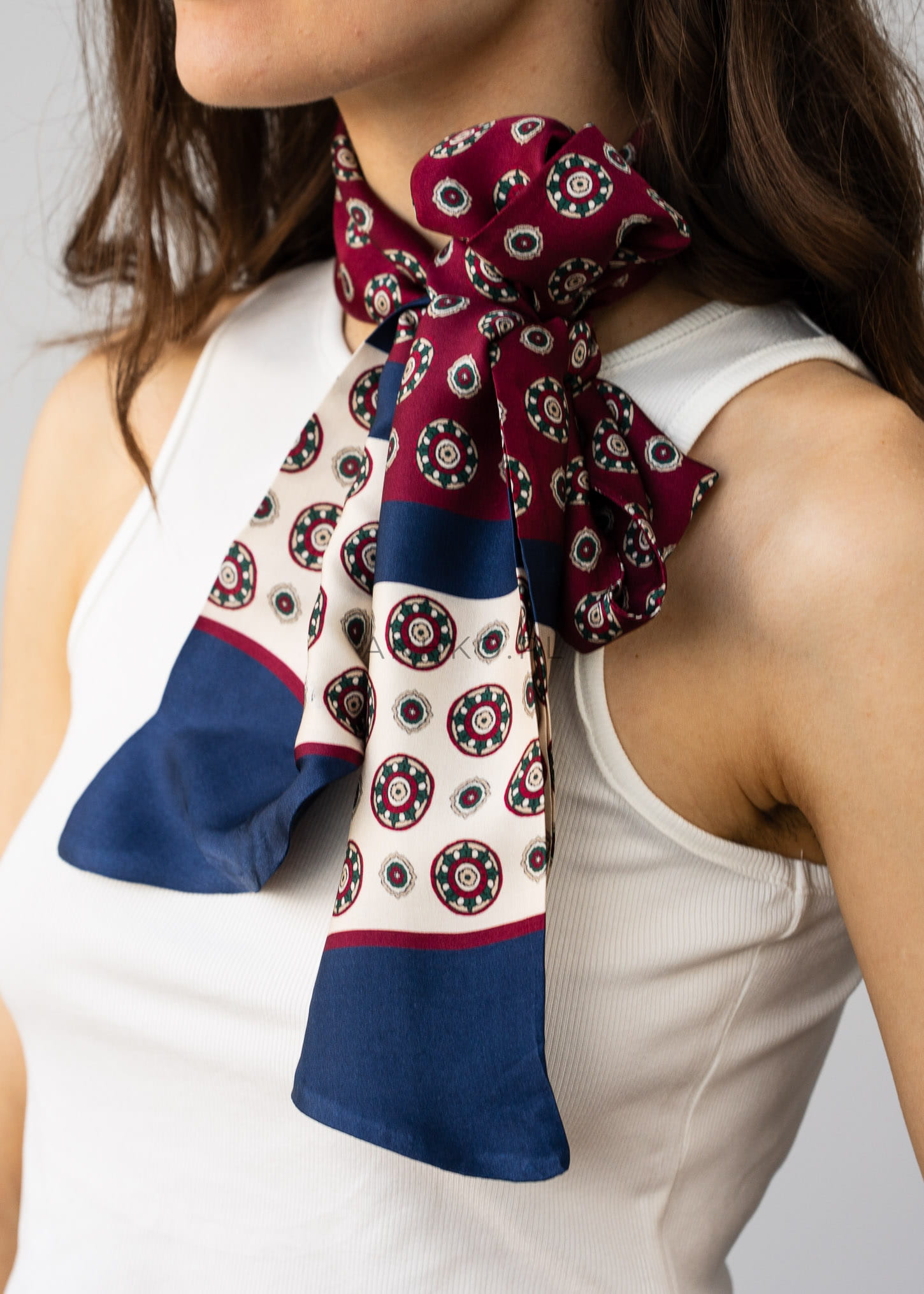 Bordowa jedwabna apaszka damska z geometrycznym wzorem i granatowym wykończeniem wiązana na szyi