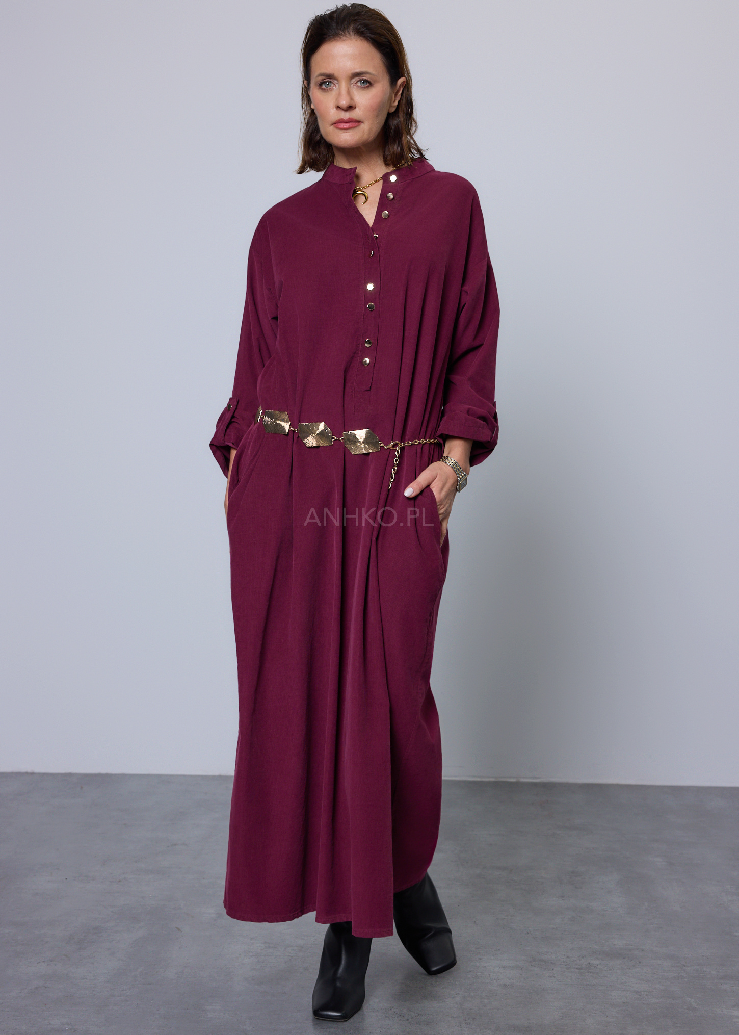 Długa sukienka damska w kolorze burgundowym o luźnym prostym kroju ze stójką i długimi rękawami z możliwością podpięcia zapinana na metalowe guziki elegancka moda damska